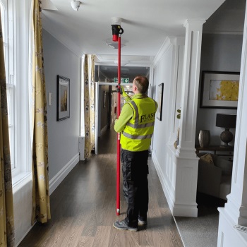 Man from FlashSecurity high-visibility jacket installing a fire alarm system for the client based in London